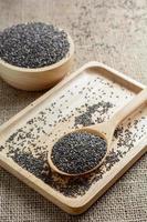Chia seed on a wooden spoon against burlap background