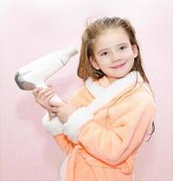 Cute smiling little girl dries hair