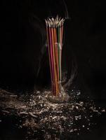 Burning incense sticks with smoke and ash on black background. photo