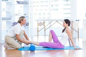 Trainer working with woman on exercise mat photo