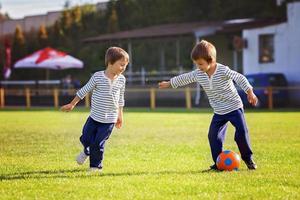 Two cute little boys, playing football