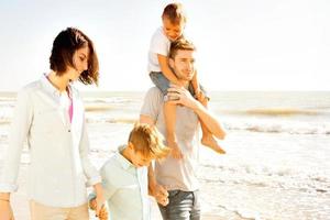familia disfrutaba caminando en la playa en el mar foto