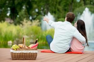 Feliz pareja romántica disfrutando de picnic en un parque cerca del lago