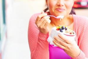 Happy, young lady enjoying frozen yogurt with fruit photo