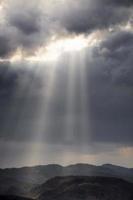 Sun Rays through the clouds illuminating the earth photo