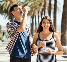 feliz pareja disfrutando el agua de botellas de plástico foto
