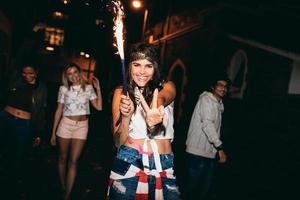 Cheerful young woman holding a sparkler enjoying in party photo