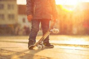 Child with skateboard on the street at sunset light photo