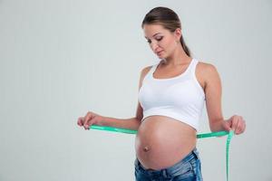 Retrato de una mujer embarazada con cinta métrica foto