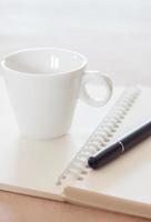 bolígrafo y cuaderno de espiral con taza de café foto