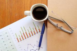 note book and chart on wooden table with coffee