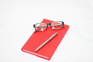 libro rojo con bolígrafo y gafas