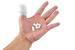 Medicines pill in hand with thumb bandage photo