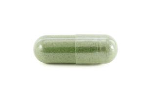 Capsule of green herbal supplement product isolated on white