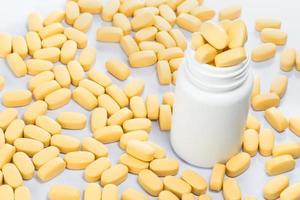 Yellow pills spilling out of a medicine bottle photo
