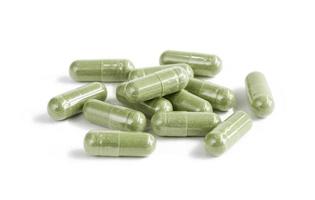 Capsules of green herbal supplement product isolated on white photo