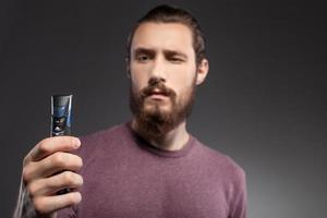 Cheerful guy with beard is thinking about shaving