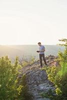 Man stands on a hill and reading a book vertical photo