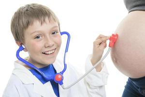 Joyful little brother listening stethoscope belly photo