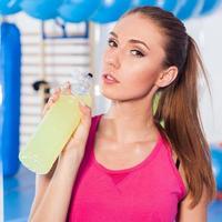 Young girl drinking isotonic drink, gym photo