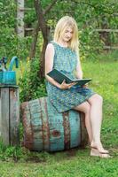Chica estudiante descalza en jardín leyendo libro con tapa azul