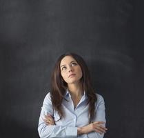 Businesswoman looking up with empty blackboard photo