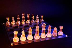 Glass chess on chessboard lit by blue and orange light photo