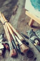Artistic paintbrushes, tubes of paint, palette knife and easel. photo