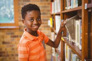 Portrait of boy selecting book in library photo
