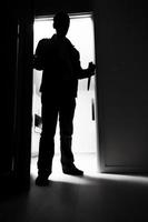 Ladrón de cuerpo entero con cuchillo entrando en cuarto oscuro foto