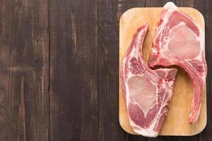 Fresh pork chops or cutlets on wooden background. photo