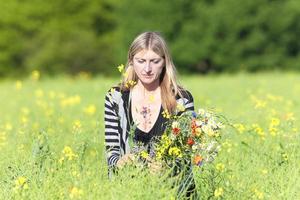 mujer recogiendo flores silvestres en el prado