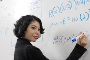 Female student writing maths equations on whiteboard photo