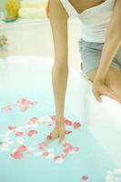 Woman putting petals into a bath tub