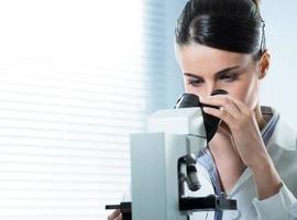 investigador femenino utilizando microscopio de cerca foto