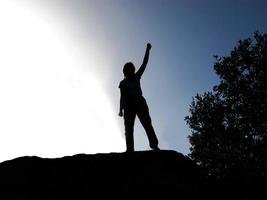 Backlit person by lifting arm as a sign of victory