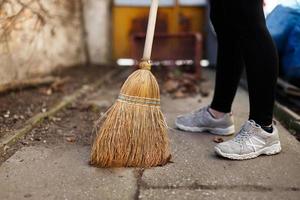 Woman sweep leaves and soil into bin photo