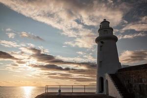 Lighthouse and sunset on the sea photo