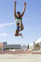 African female athlete mid-air during long jump photo