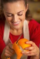 Retrato de joven ama de casa quitando la cáscara de naranja