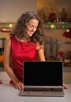 Housewife looking on laptop blank screen in christmas kitchen photo