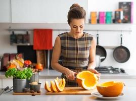 young housewife cutting pumpkin in kitchen