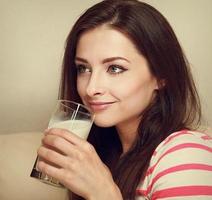 Smiling woman drinking milk and looking happy. Closeup portrait photo