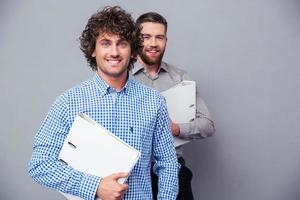 Two cheerful businessmen holding folders