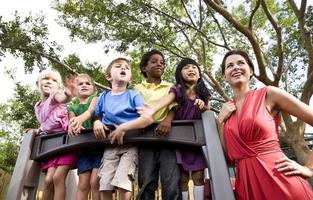 Preschool teacher with students on playground looking out photo