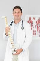 Handsome cheerful doctor holding skeleton model