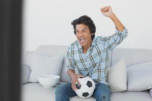 aficionado al fútbol animando mientras mira televisión