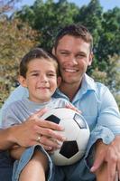 Cheerful dad and son with football photo