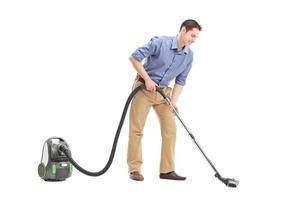 Cheerful young man using a vacuum cleaner photo