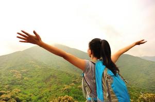 animando senderismo mujer brazos abiertos en el pico de la montaña